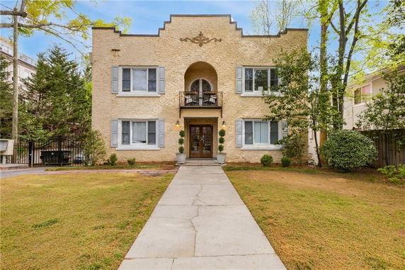 Front view of a two-story stucco house with decorative balcony and windows.