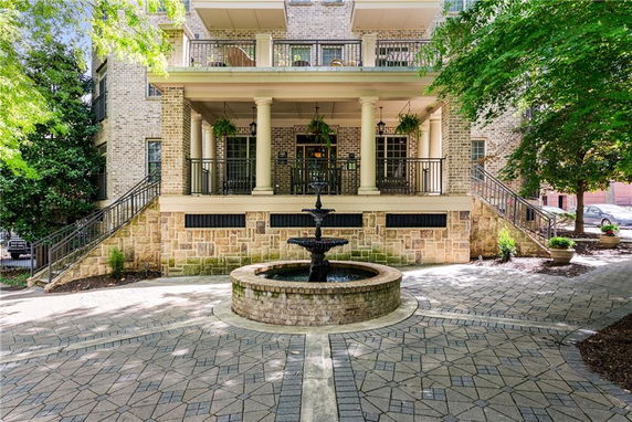 Front view of a multi-story building with a brick and stone exterior and a central fountain.