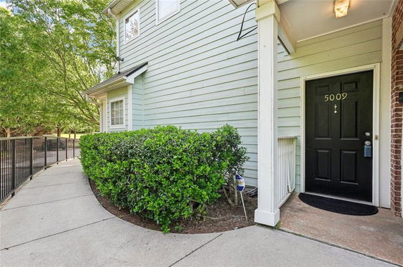Front view of a house with a black front door and light green siding.