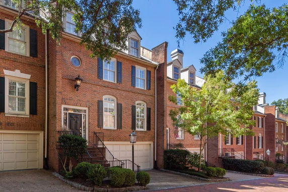 Front view of a multi-story townhome with brick exterior and garage.