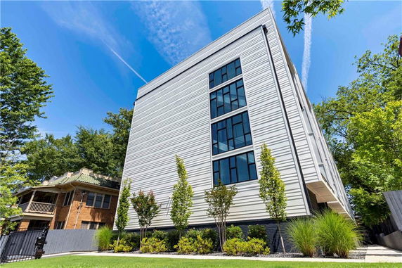 Front view of a modern multi-story building with large windows and a sleek design.