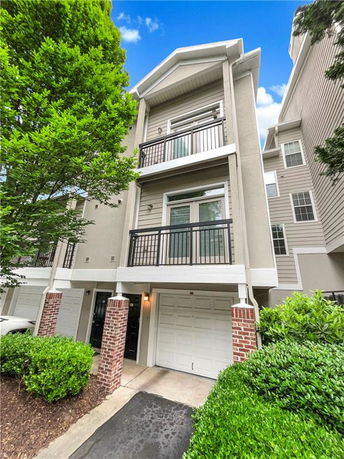 Front view of a multi-story townhouse with balconies and an attached garage.