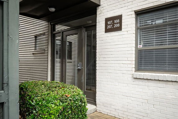 Front view of a building entrance with a glass door and an adjacent window.