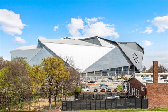 Front view of a large, modern stadium with angular design and prominent logo.