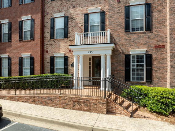 Front view of a brick building with a porch entrance and black shutters.