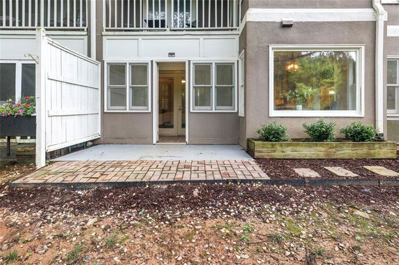 Front view of a building with a ground-floor patio and surrounding plants.