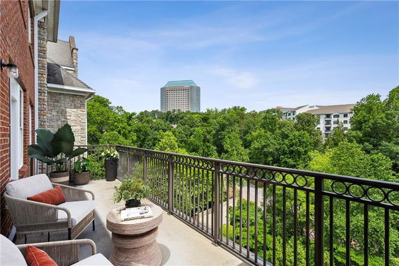 Balcony view overlooking lush greenery and distant buildings.