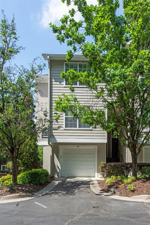 Front view of a townhouse with a garage on the ground level and windows on the upper floors.