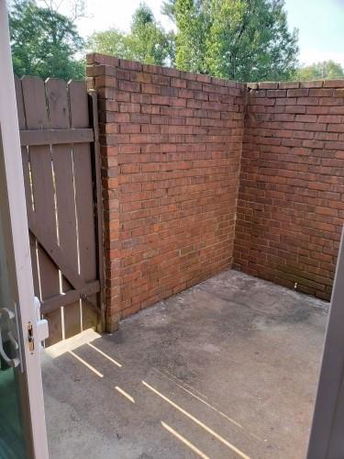 A small outdoor brick-walled area with a wooden gate.