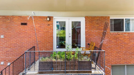 Front view of a building with a small balcony, double glass doors, and brick exterior.