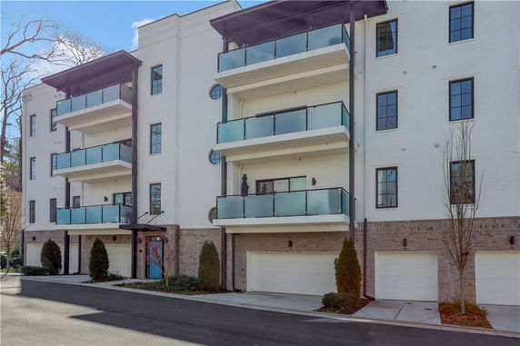 Front view of a multi-story residential building with multiple balconies and garages.