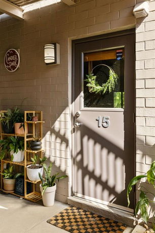 Front view of a building entrance with a door labeled number 15, surrounded by potted plants and simple decor.