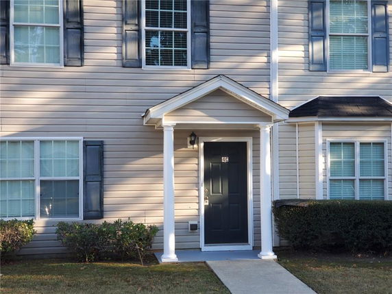 Front view of a building entrance with a covered porch and white columns.