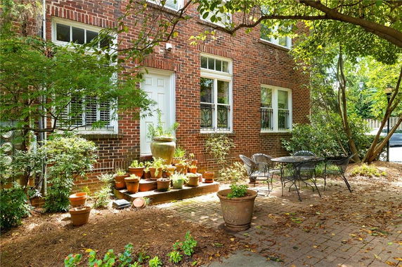 Front view of a brick house with a small patio and potted plants.