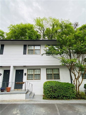 Front view of a two-story house with white siding and black shutters.