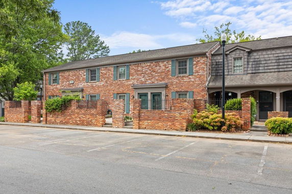Front view of a brick townhouse with a flat roof and small garden area.