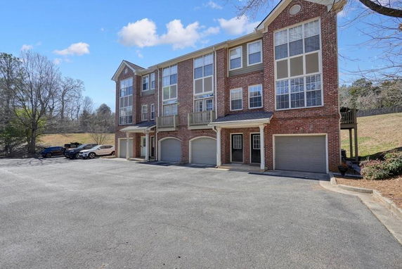 Front view of a three-story brick apartment building with multiple garages.