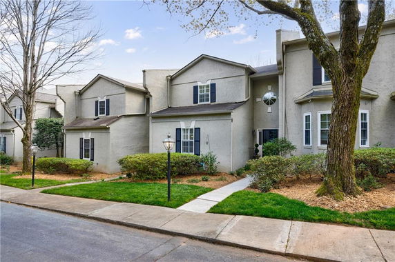 Front view of a townhouse with a light gray exterior and a small landscaped front yard.