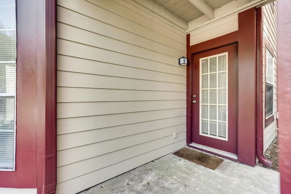 Exterior view of a house corner featuring a door with a window grid design and surrounding siding.