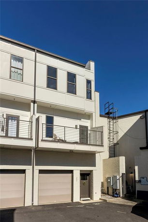 Front view of a multi-story building with balconies and a garage.