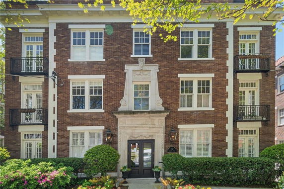 Front view of a multi-story brick building with large windows and decorative balconies.