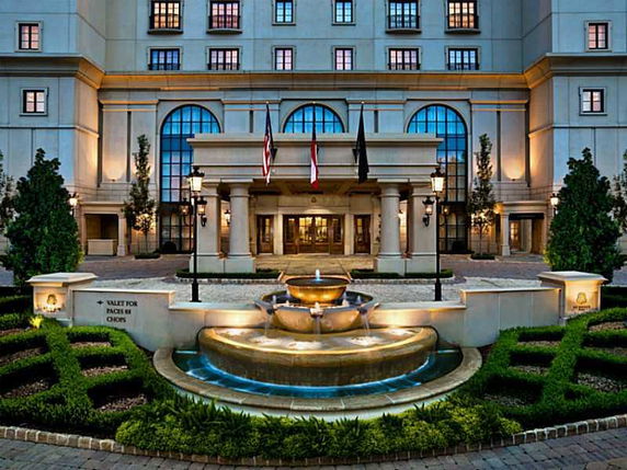 Front view of a multi-story building with a grand entrance and water fountain.