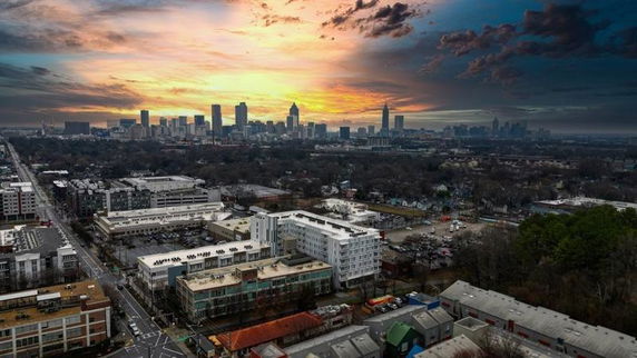 Panoramic view of a city skyline at sunset, with buildings and roads visible.