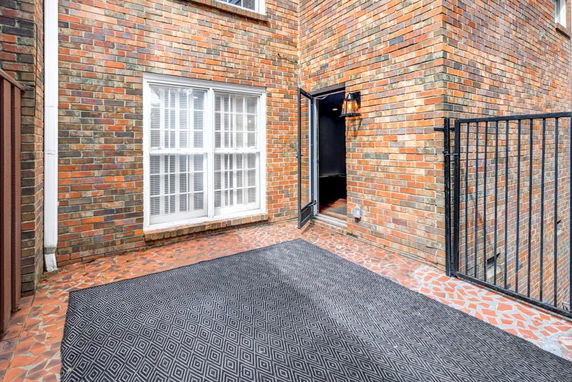 Brick exterior view of a building with a large window and open door leading to an interior.