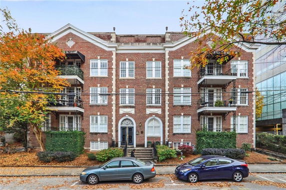 Front view of a four-story brick apartment building with balconies.