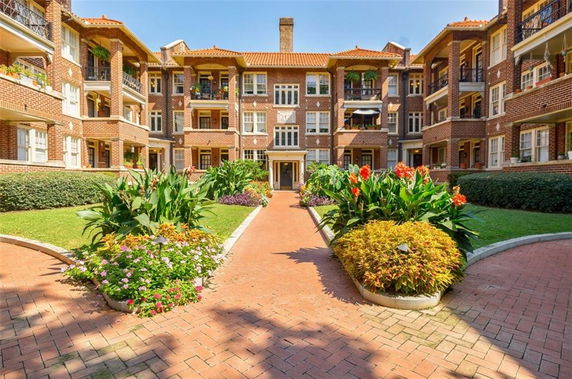 Front view of a multi-story brick apartment building with balconies and landscaped garden.
