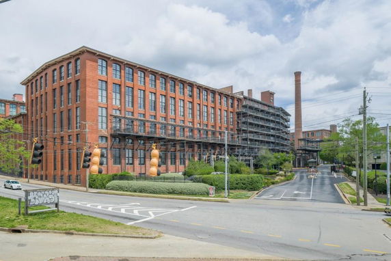 Front view of a large brick industrial building with multiple windows and chimneys.