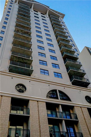 Front view of a tall multi-story residential building with balconies.