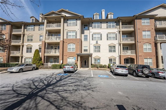 Front view of a multi-story residential building with a parking area in front.