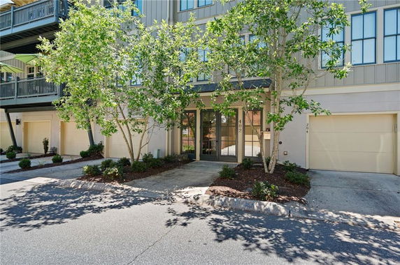 Front view of a multi-story residential building with garage entrances and trees in front.