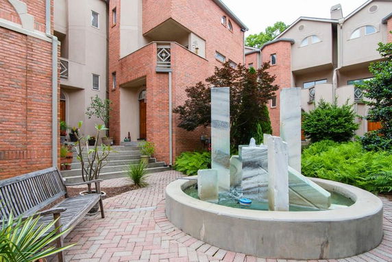 Front view of a multi-story building with red brick facade and a decorative fountain in the courtyard.