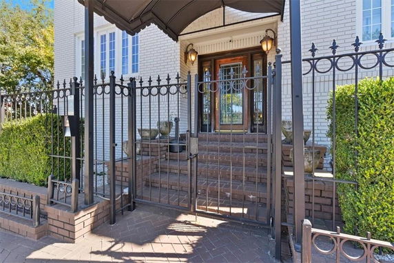 Front view of a house with a gated entrance and brick steps.