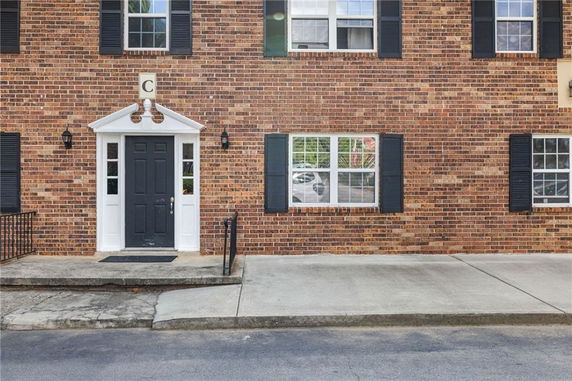 Front view of a brick building with a black door and windows.