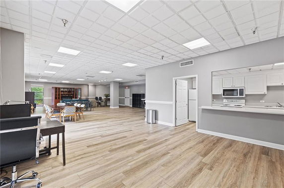 Spacious indoor area with desks, chairs, and a kitchenette, suitable for recreational activities or gatherings.