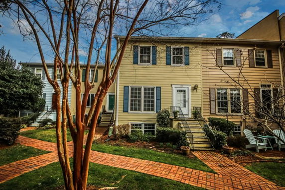 Front view of a two-story townhouse with a brick walkway and stairs leading to the entrance.