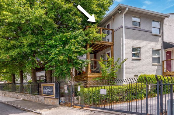 Front view of a two-story building with a wooden balcony and metal fence.