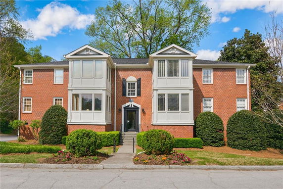 Front view of a two-story red brick house with prominent bay windows.