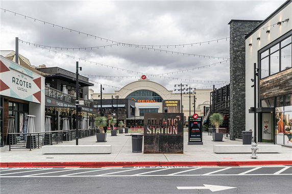 Front view of a commercial area with multiple storefronts and a cinema entrance.