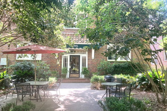 Front view of a brick building with a central entrance surrounded by greenery.