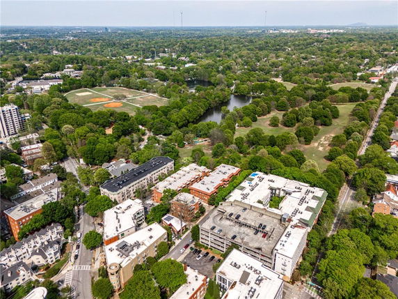 Aerial panoramic view of a residential area with surrounding greenery and a park with a lake.