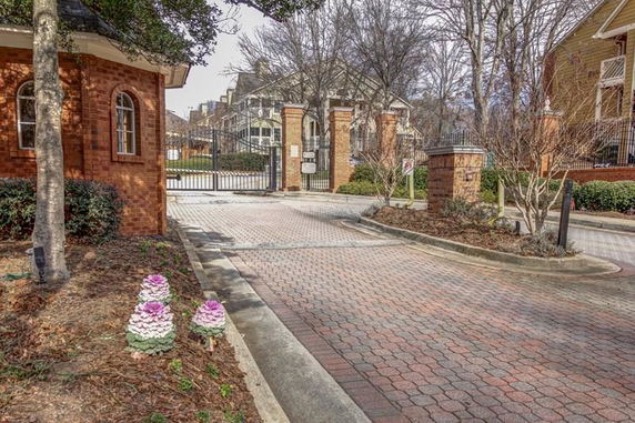 Front view of a gated community entrance with brick pillars and iron gates.