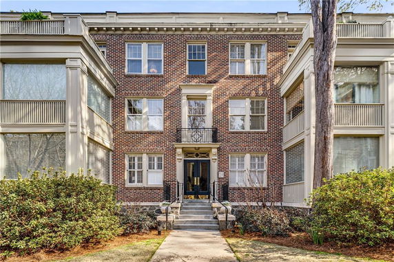 Front view of a multi-story brick building with large windows.