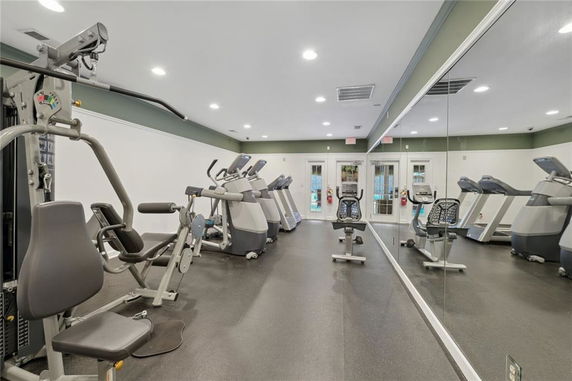 Interior view of a gym with exercise equipment and mirrors on the wall.