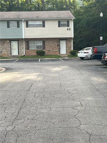 Front view of a two-story building with a parking area in front.