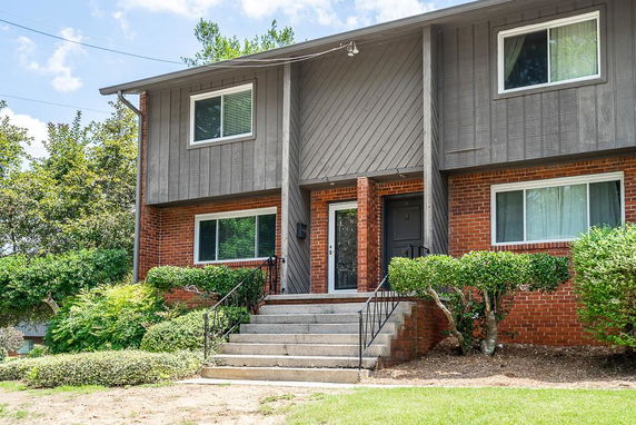 Front view of a two-story brick house with steps leading to the entrance.