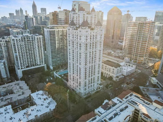 Aerial view of a cityscape featuring a tall multi-story building surrounded by other high-rise structures.
